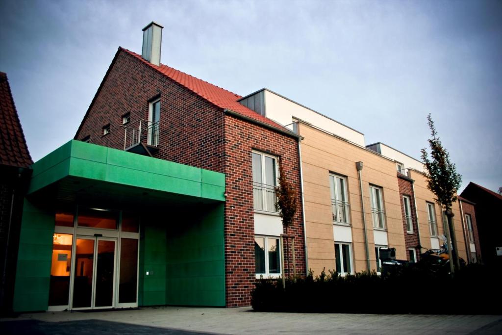 un bâtiment en briques rouges avec un toit vert dans l'établissement Hotel Brauhaus Stephanus, à Coesfeld