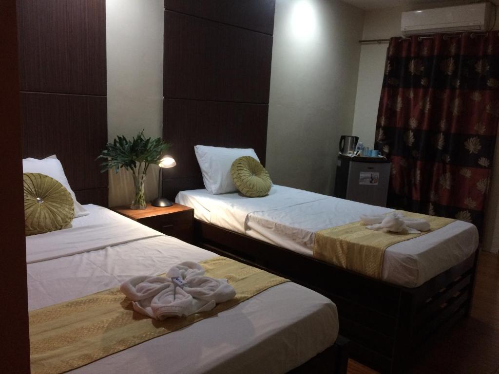 2 Betten in einem Hotelzimmer mit Handtüchern darauf in der Unterkunft Mañana Hotel in Olongapo