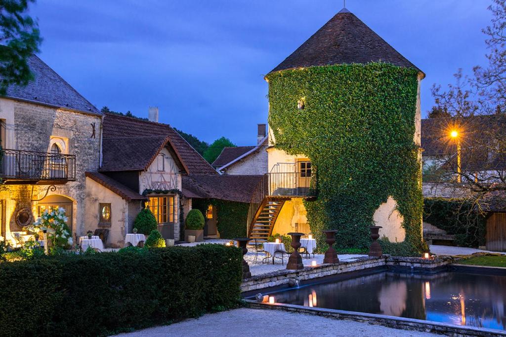 une maison recouverte de lierre avec une piscine en face de celle-ci dans l'établissement Château de Courban and Spa Nuxe, à Courban