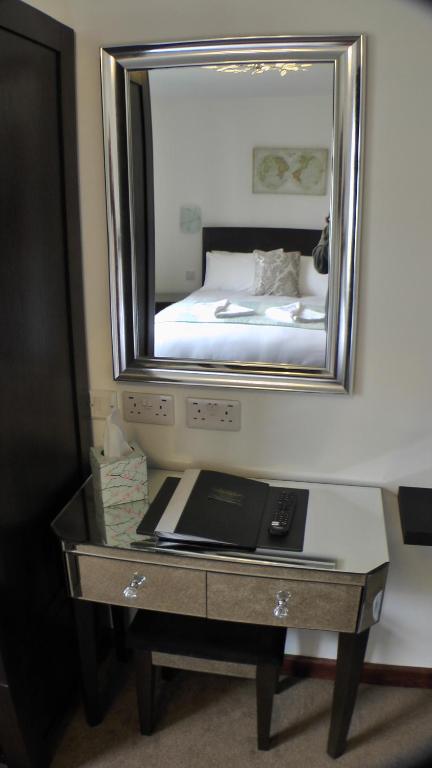a mirror above a desk with a bed in a room at Bay Lodge in Birchington