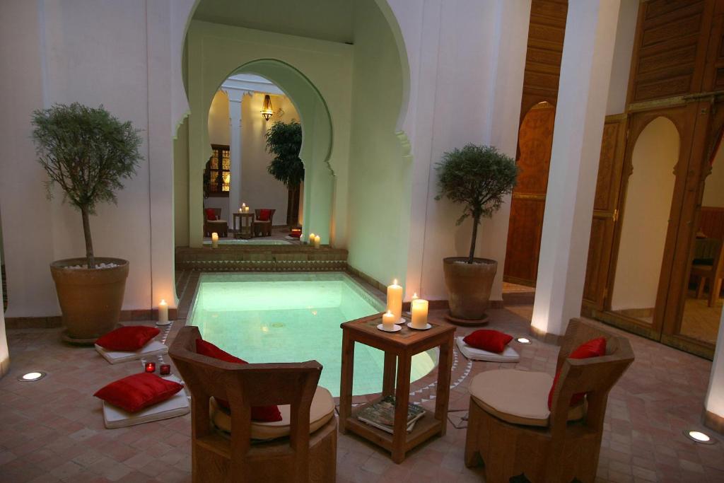 una piscina en un edificio con sillas y velas en Riad Chameau FDC Hôtel SPA, en Marrakech