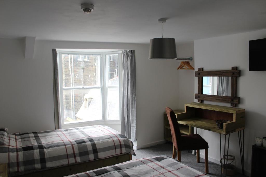 1 dormitorio con cama y piano junto a una ventana en The Pier Hotel en Aberystwyth