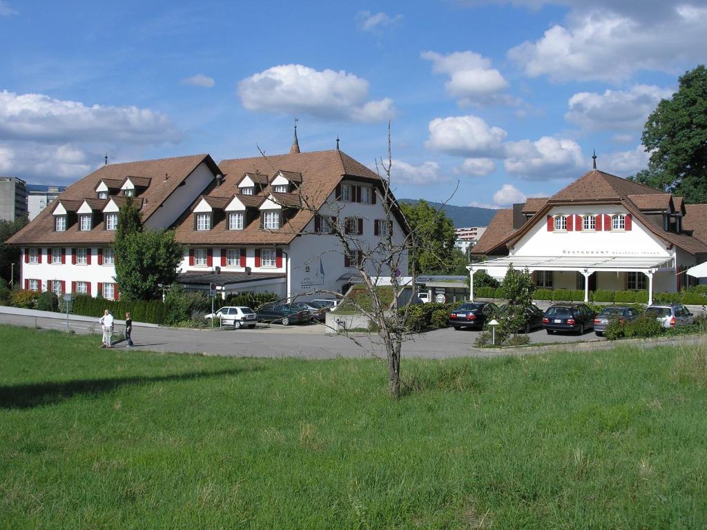 un grupo de edificios con coches estacionados en un estacionamiento en Hotel Schlössli en Ipsach