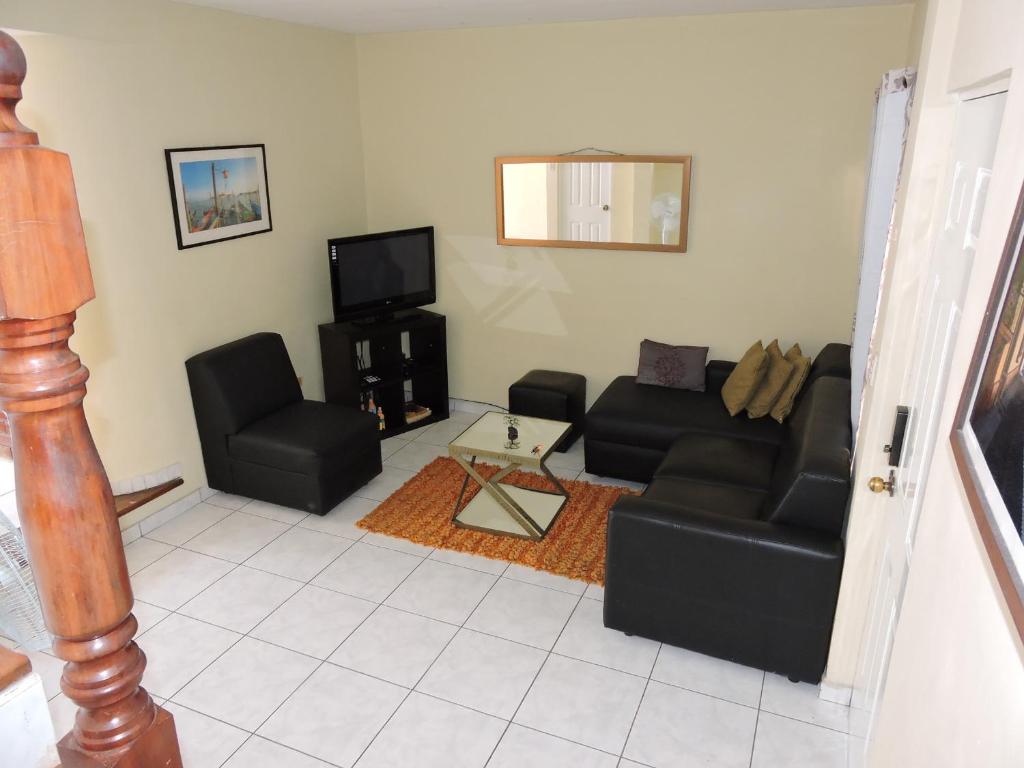 a living room with black couches and a tv at Cumbres de San Francisco in San Salvador