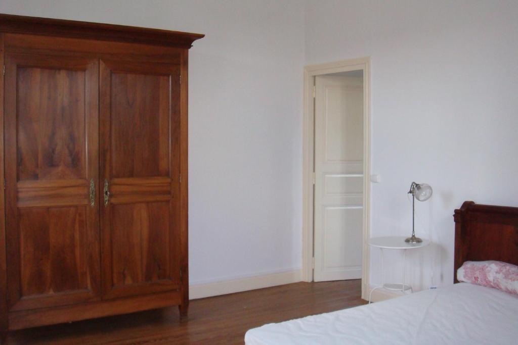1 dormitorio con armario de madera junto a la cama en Le Petit Carpia, en Castillon-de-Castets