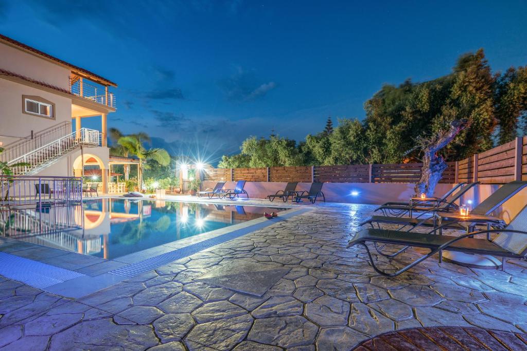 a swimming pool with chairs and a building at Armonia Boutique Hotel in Meson Yerakarion