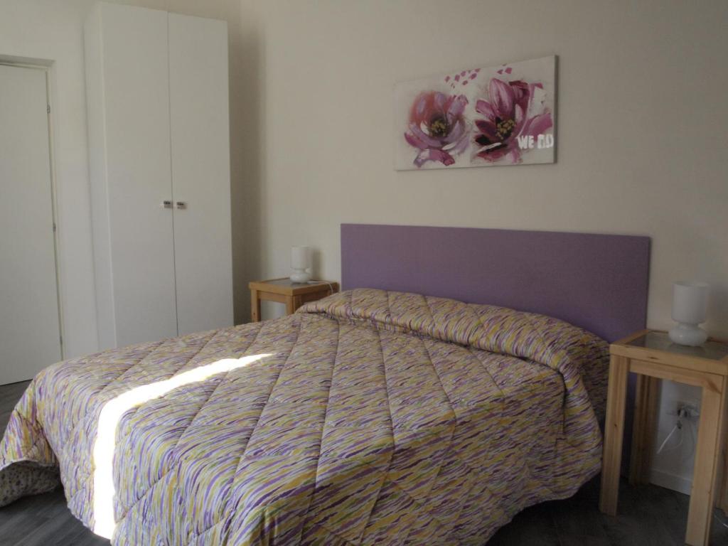 um quarto com uma cama com um edredão e duas mesas em B&B Dafne Marsala Centro em Marsala