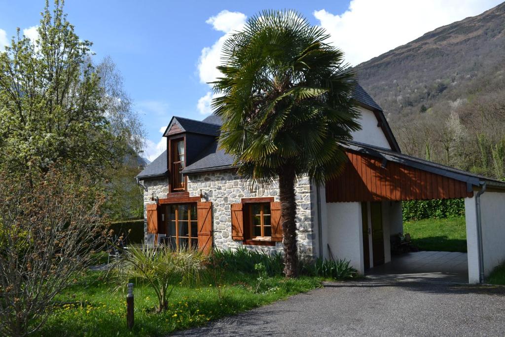 a stone house with a palm tree in front of it at Enço deth terralh in Pierrefitte-Nestalas