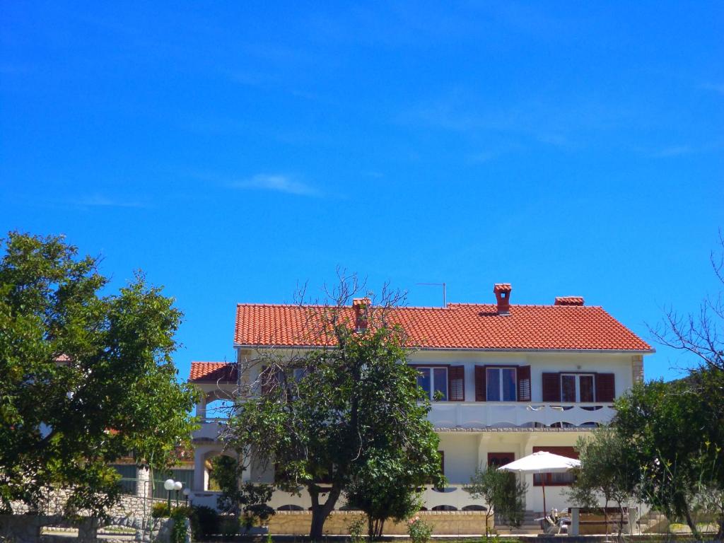 una casa grande con techo rojo y árboles en Apartments Vesna, en Rab