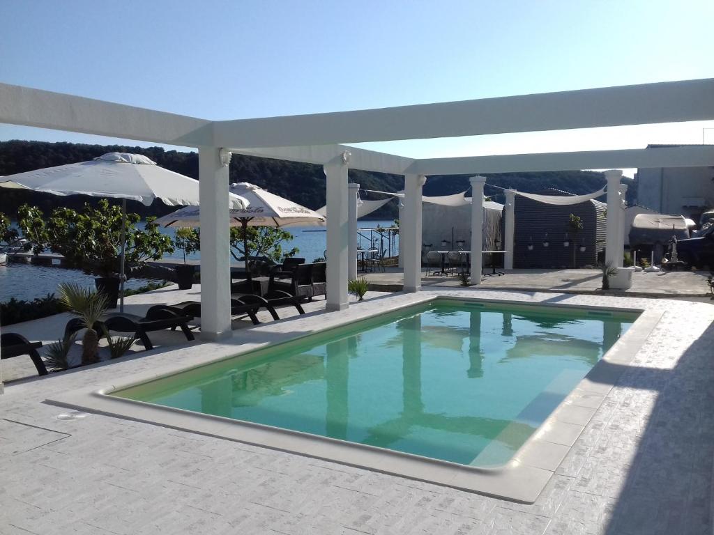 a swimming pool on a patio with an umbrella at Guesthouse Raffaello in Kampor