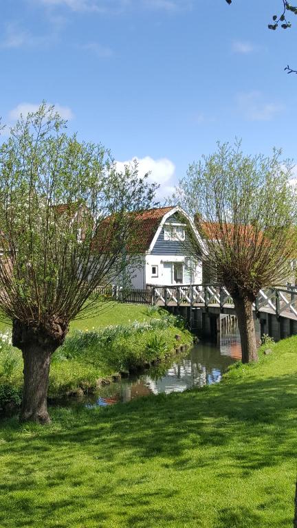 een huis met een brug over een rivier met twee bomen bij Vakantiehuis uus Klinte Hindeloopen in Hindeloopen