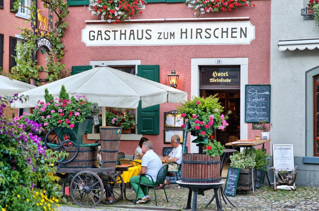 zwei Personen sitzen an einem Tisch vor einem Restaurant in der Unterkunft Gasthaus Zum Hirschen in Staufen im Breisgau