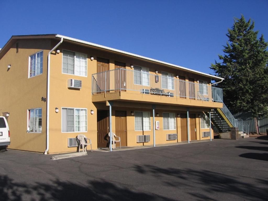 ein gelbes Gebäude mit Balkon und Parkplatz in der Unterkunft Heritage House Motel in Prescott