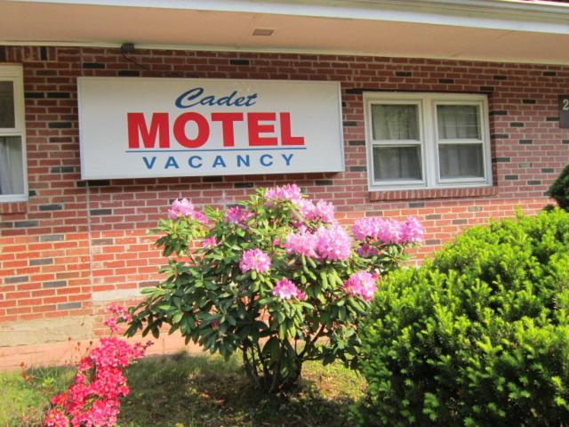 un cartello di un motel su un edificio di mattoni con fiori rosa di Cadet Motel a Cornwall-on-Hudson