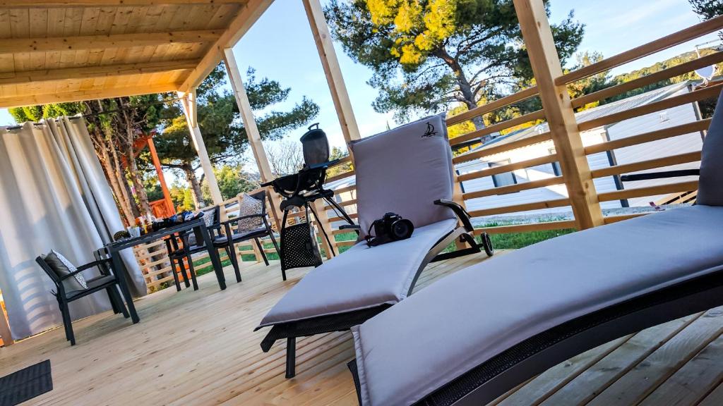 un porche con sillas y un banco en una terraza de madera en Adrijela Mobile Home, en Jezera