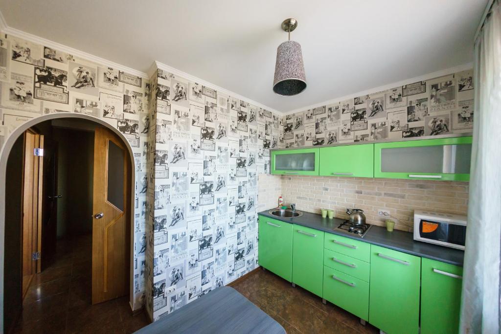 una cocina con armarios verdes y una pared de ladrillo en Apartment Pink on Tereshkovoy 10/5 en Oremburgo