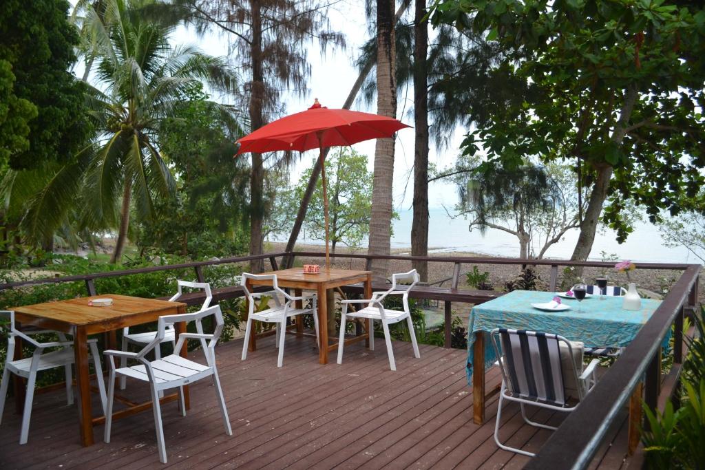 a wooden deck with tables and chairs and an umbrella at Baan Chid Talay in Ko Chang
