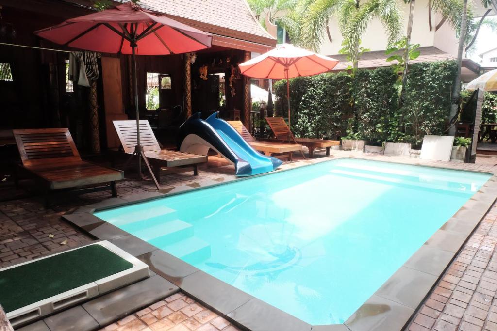 a swimming pool with a slide and chairs and umbrellas at Orchid Resort in Lat Krabang