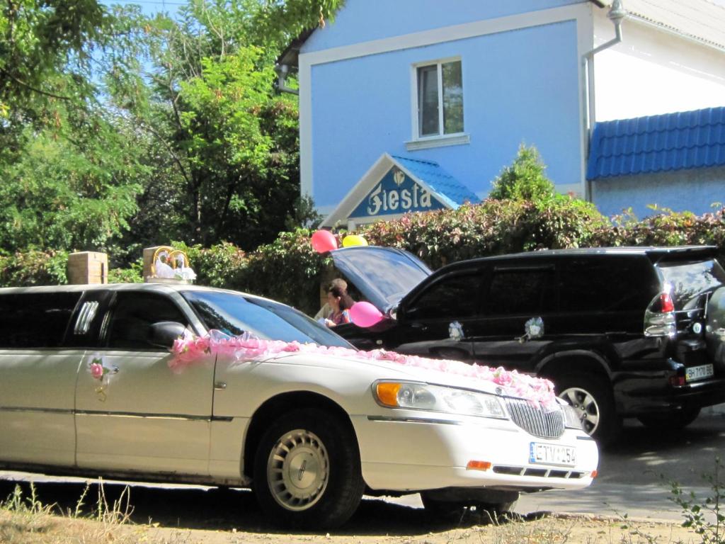 Ein weißes Auto mit rosa Blumen auf der Haube und einem schwarzen Truck. in der Unterkunft Economy Hotel Fiesta in Izmail
