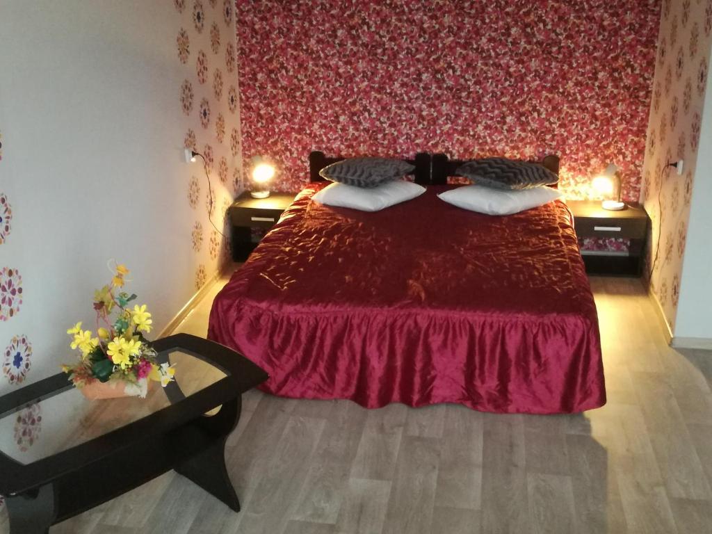 Kalbakas Apartamenti في سميلتين: غرفة نوم بسرير ولحاف احمر