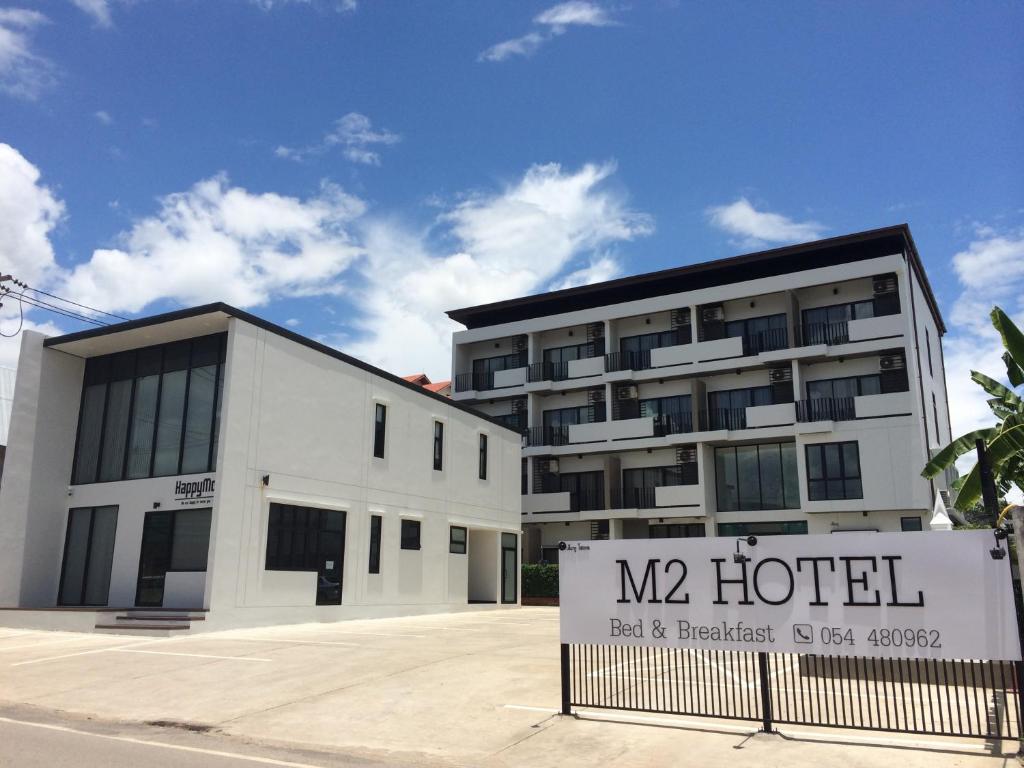 a hotel with a sign in front of a building at M2 Hotel in Phayao