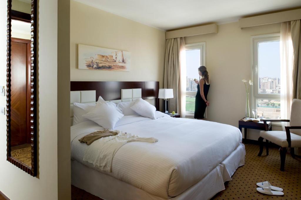 a woman standing in a hotel room with a bed at Barceló Cairo Pyramids in Cairo
