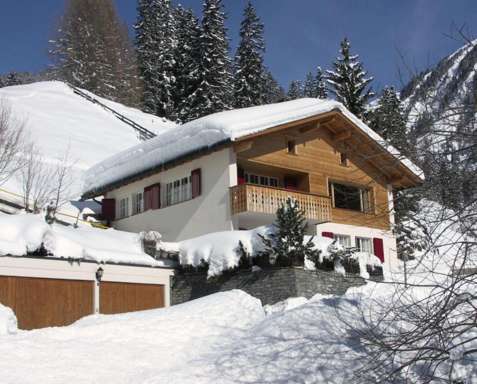 a house covered in snow with trees and mountains at Chalet Im Wieselti in Langwies
