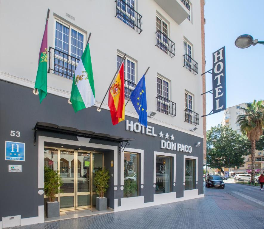 a hotel with flags hanging outside of it at Hotel Don Paco in Málaga