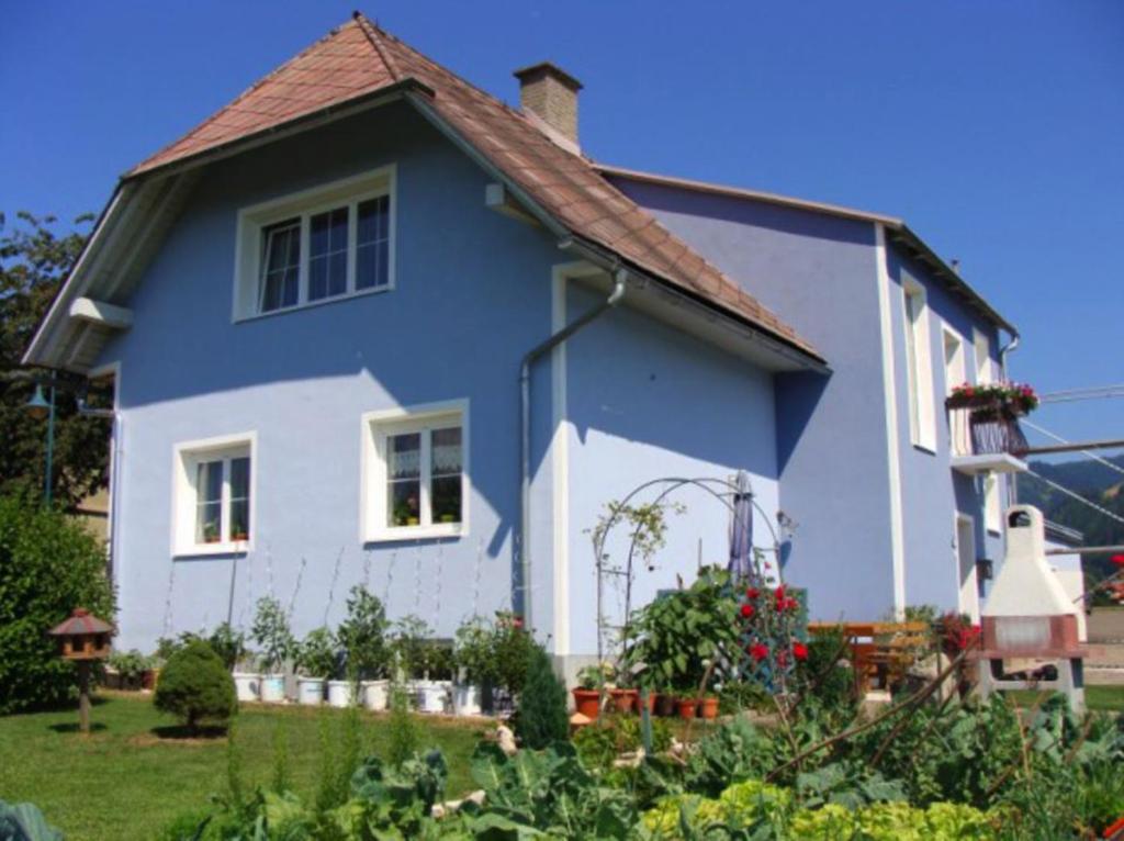 ein blau-weißes Haus mit einem Garten in der Unterkunft Pension Kisela in Fohnsdorf