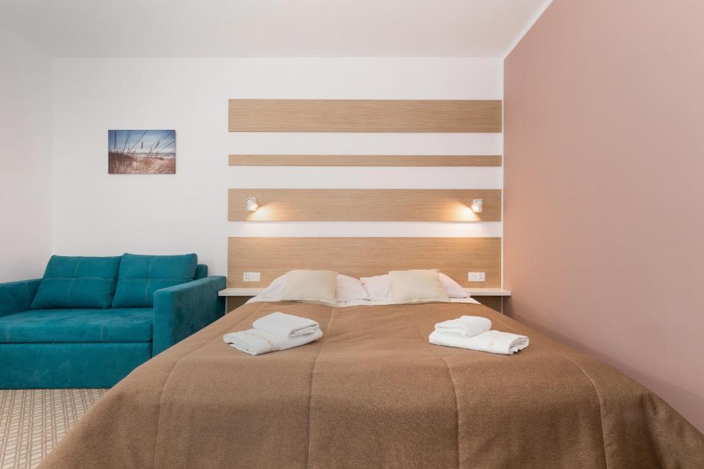 ein Schlafzimmer mit einem Bett und einer blauen Couch in der Unterkunft Willa Arielka in Rewal