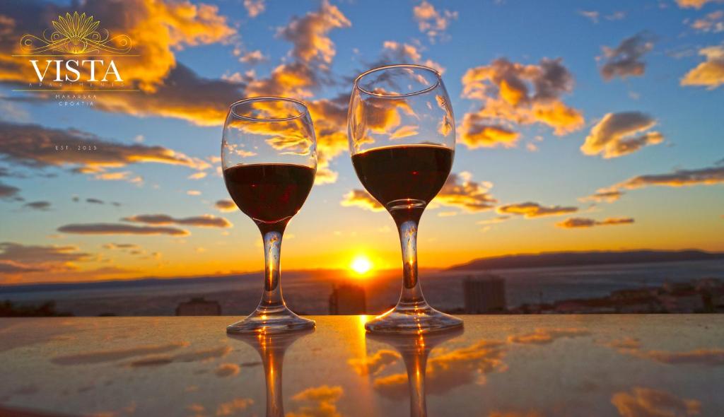 Apartment Vista Makarska في ماكارسكا: كأسين من النبيذ مع غروب الشمس في الخلفية