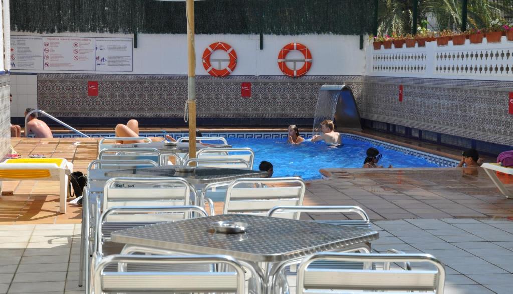 カレーリャにあるアパートホテル サファリのテーブルと椅子、水中の人々が備わるプールを提供しています。