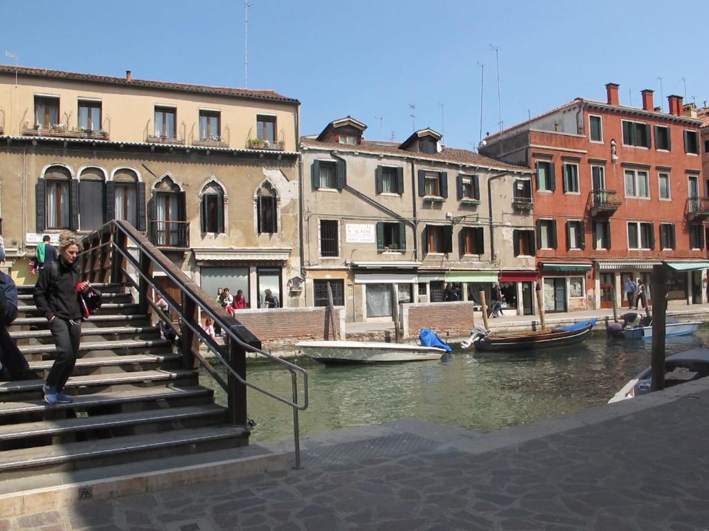 a woman walking down stairs next to a canal with buildings at Casa Di PrimaVera in Venice