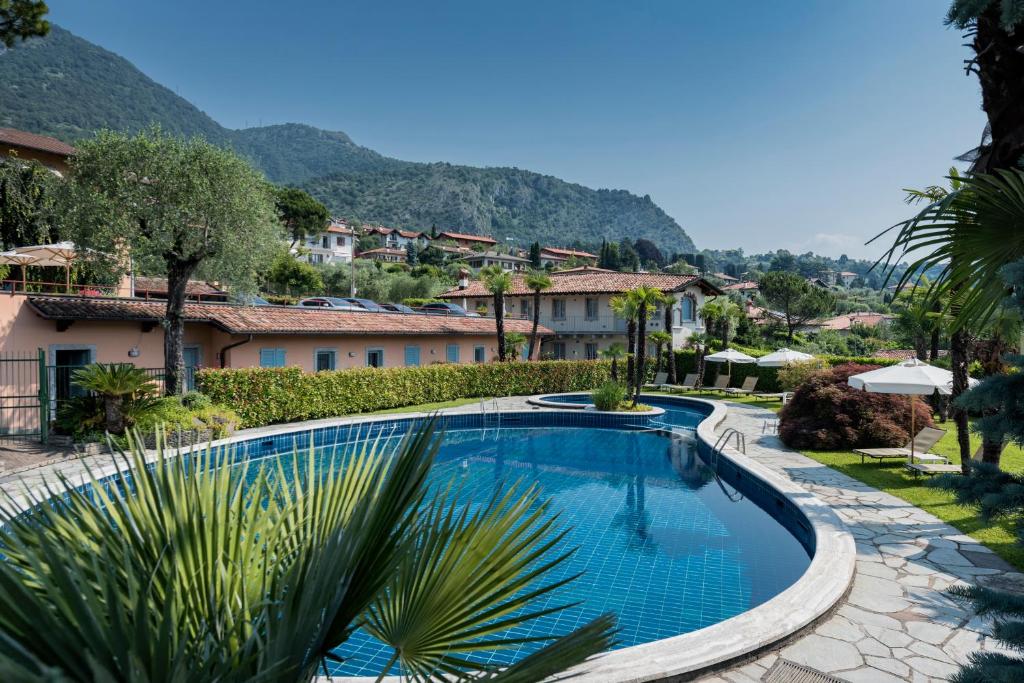 a swimming pool in a resort with mountains in the background at Villa Edy Apartments in Tremezzo