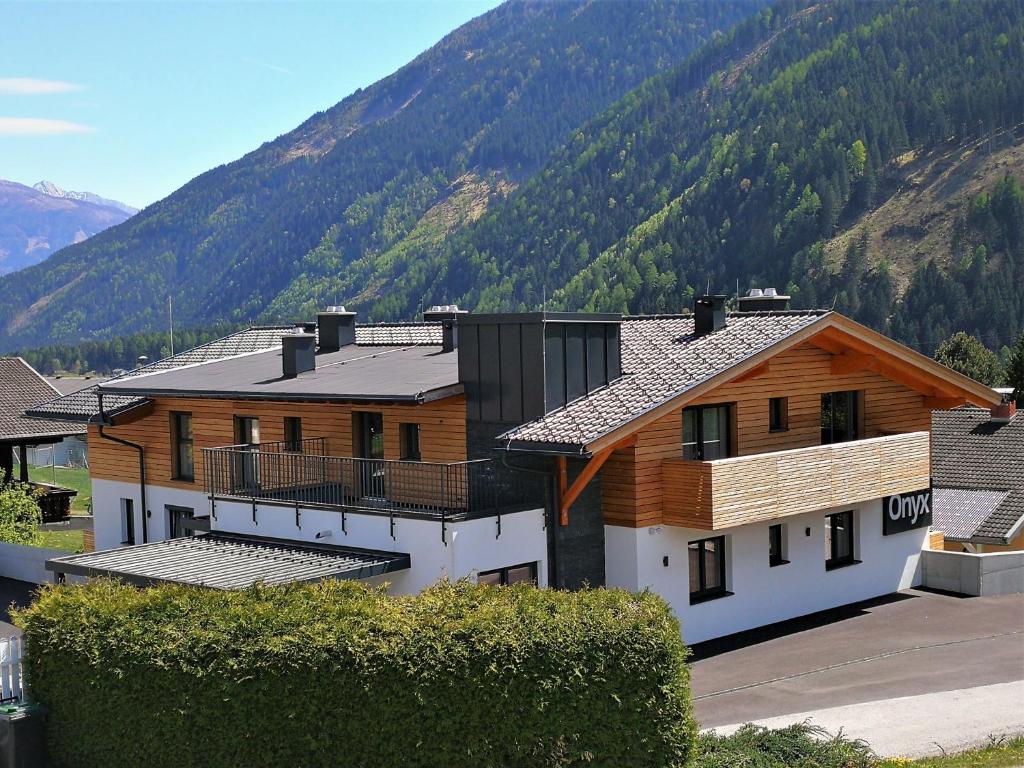 ein großes Holzhaus mit einem Berg im Hintergrund in der Unterkunft Appartements Onyx in Flattach