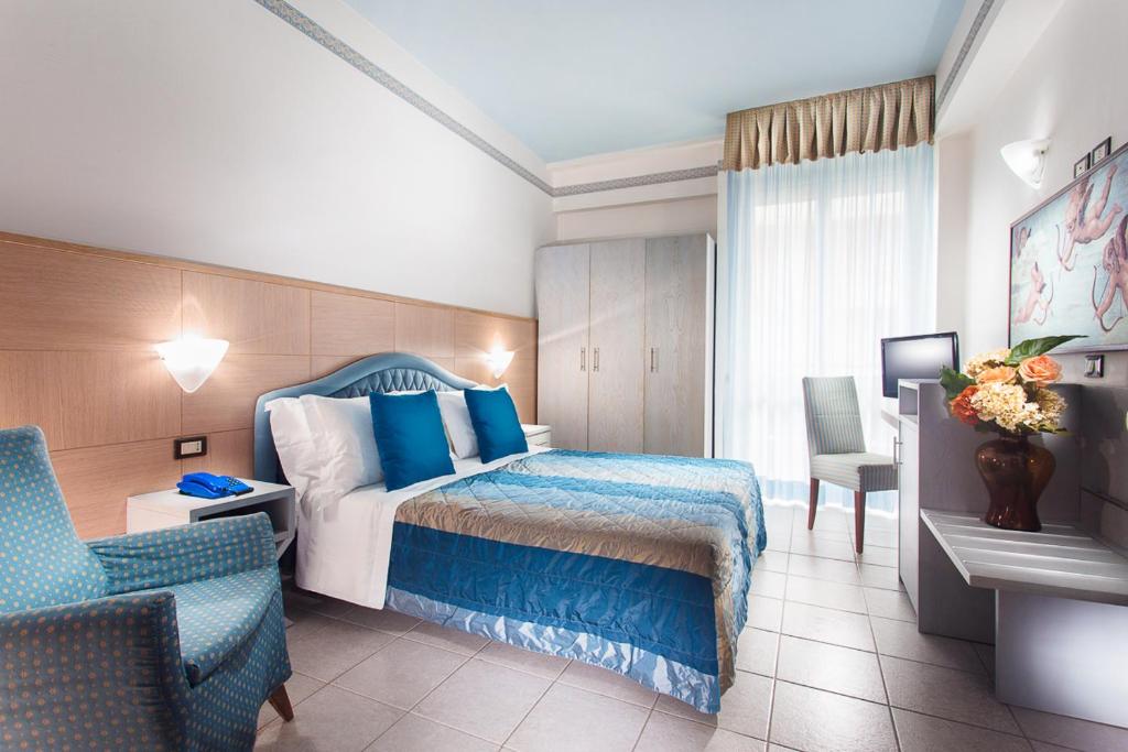 a hotel room with a bed and a chair at Hotel Imperiale in Milano Marittima
