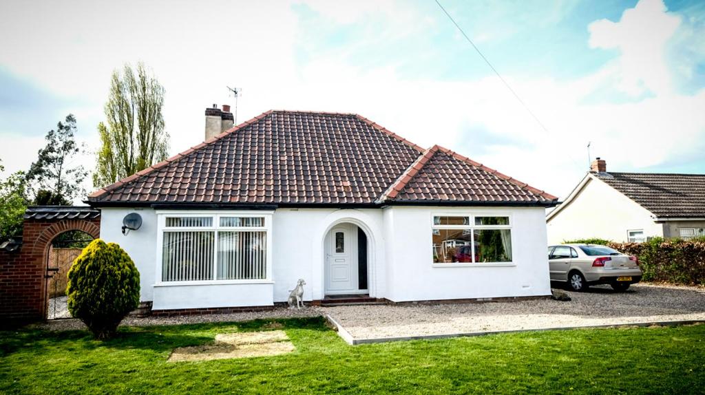 a white house with a dog sitting in the front yard at Marvene in Thornaby on Tees