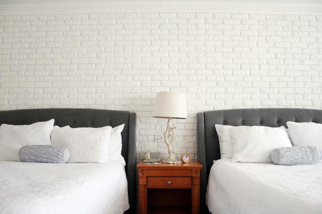 two beds with white pillows and a table with a lamp at Green Acres Inn in Kingston