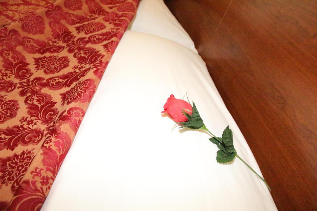 a red flower on the side of a white dress at Hotel Mirage in Rome