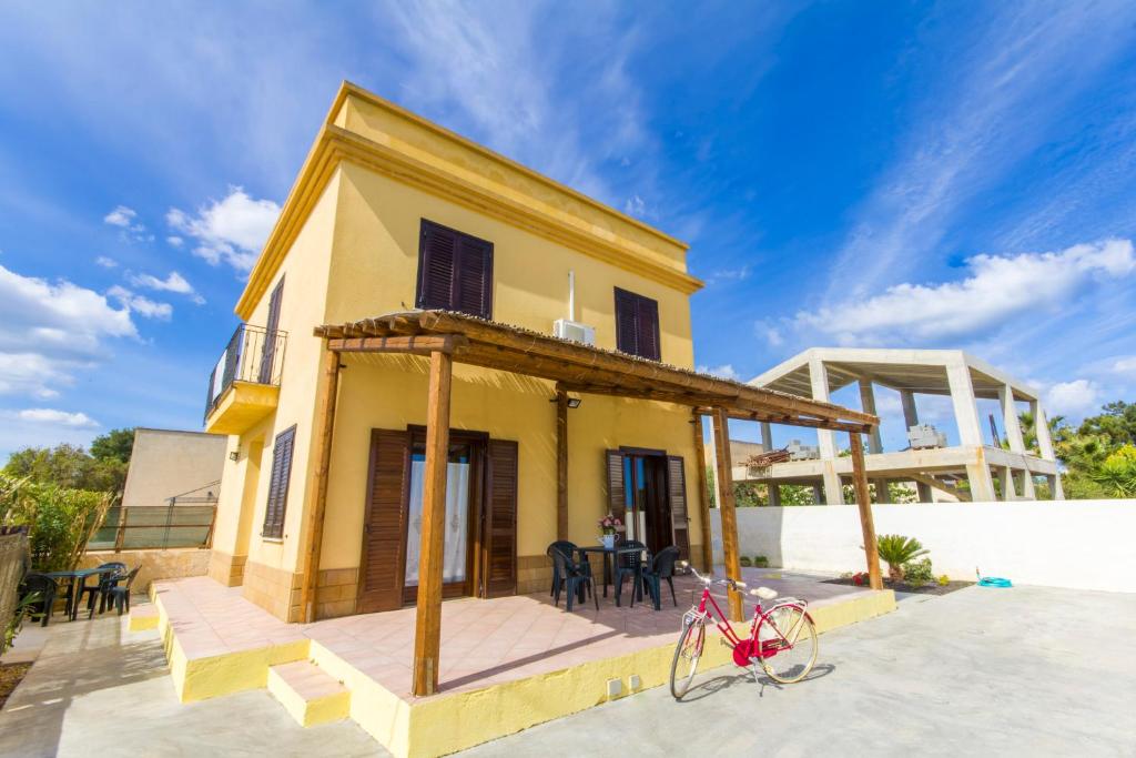 una casa con una bicicleta roja estacionada frente a ella en Appartamenti Elios en Birgi Vecchi