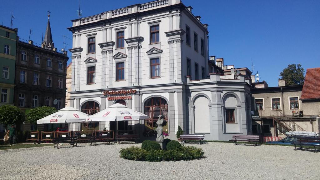 a white building with tables and umbrellas in front of it at Dolnośląski in Ząbkowice Śląskie