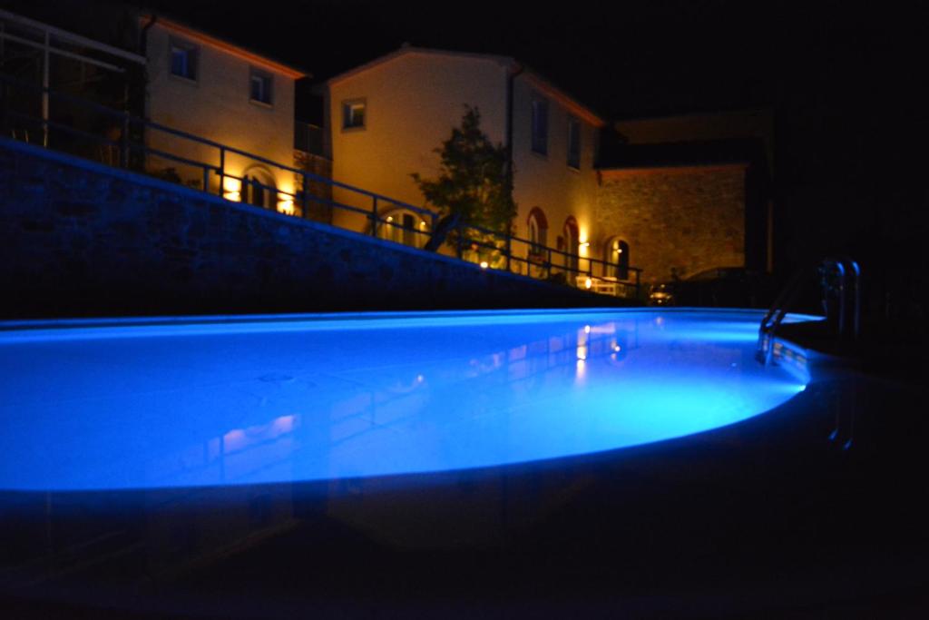 uma grande piscina à noite com um edifício ao fundo em Podere Delle Fanciulle em Pistoia