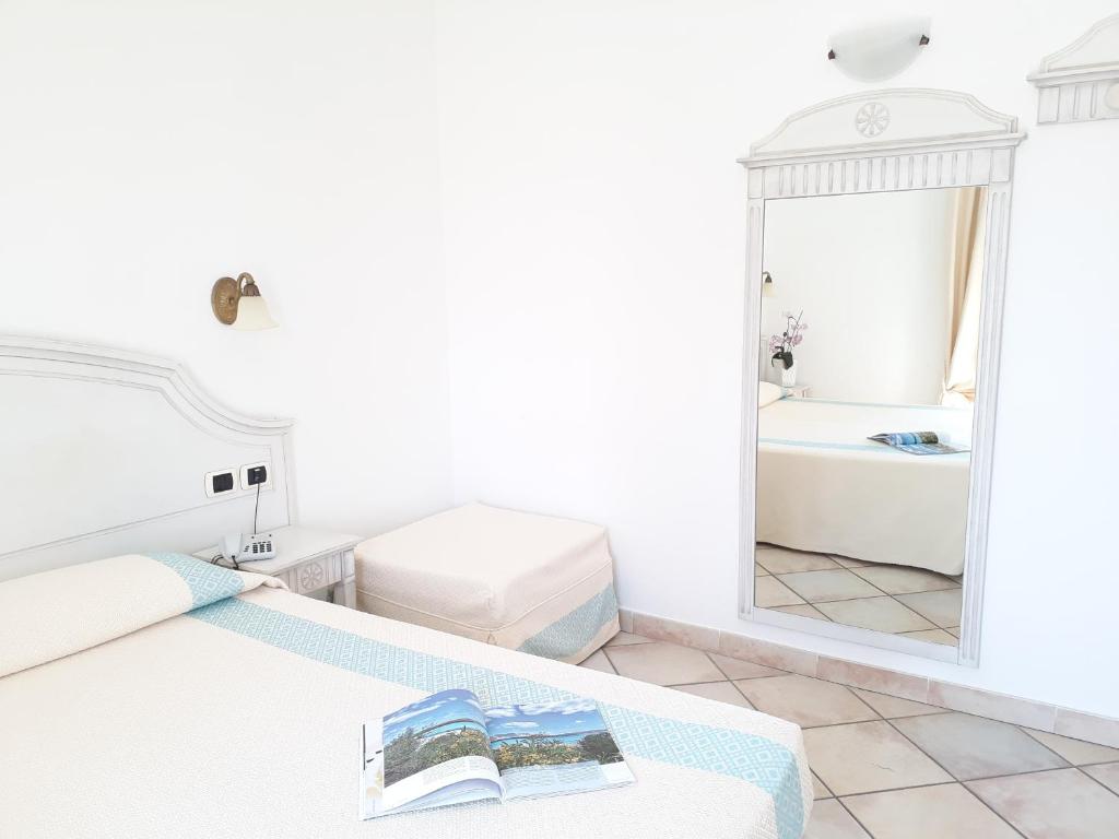 biały pokój z łóżkiem i lustrem w obiekcie Castello Di Tavolara w mieście Porto San Paolo
