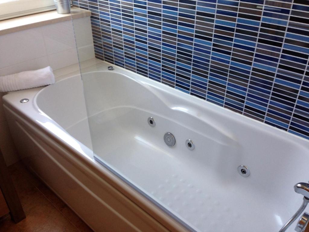 a white bath tub in a bathroom with blue tiles at Âncora Boutique Apartments in Lagos