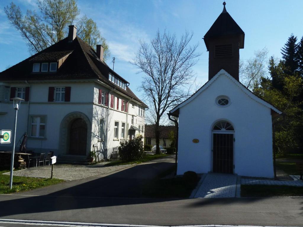 a white building with a clock tower next to a street at Altes Schulhaus in Argenbühl