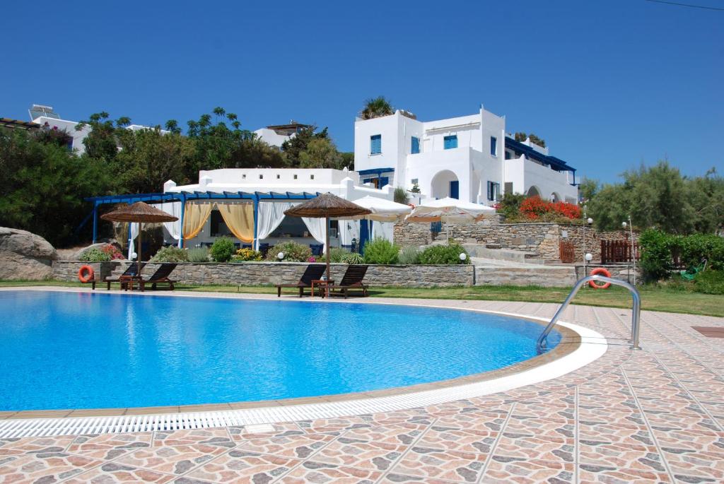une piscine avec des chaises et une maison en arrière-plan dans l'établissement Koulas Pension - Red Lake, à Ágios Prokópios