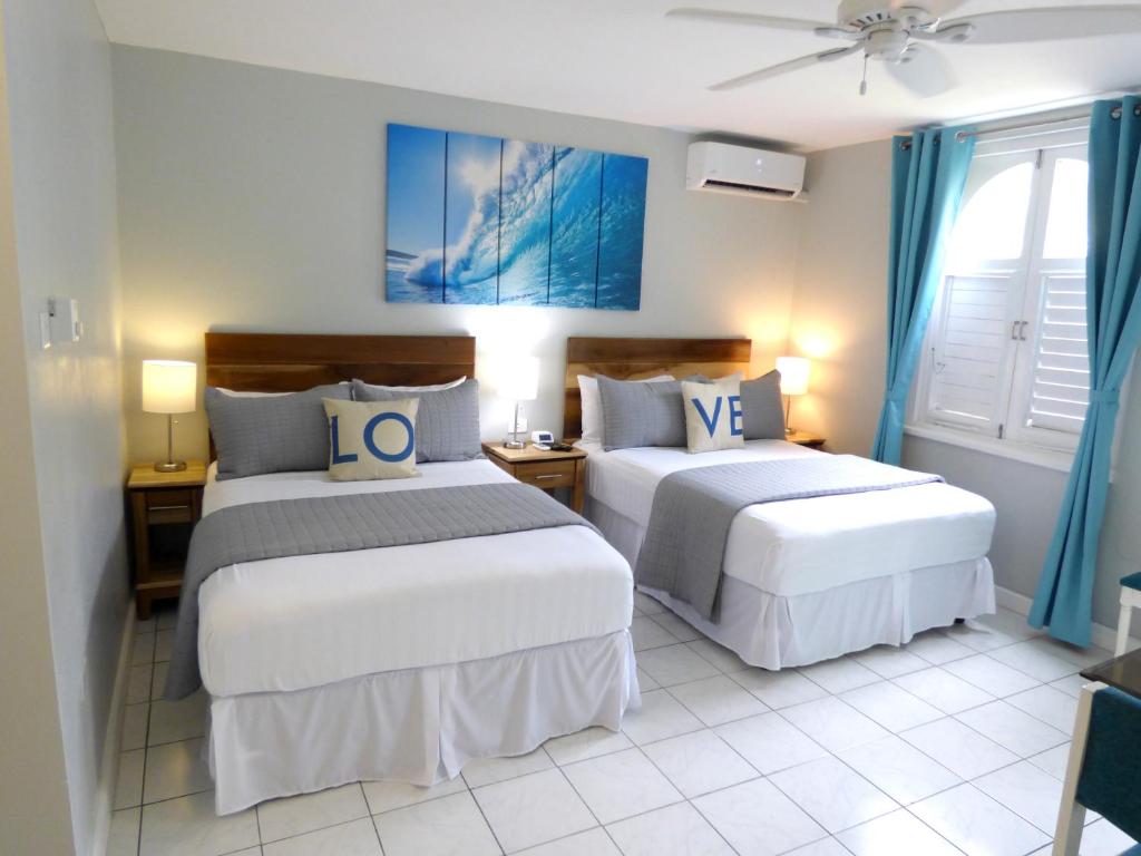 two beds in a room with blue curtains at Beach Studio 4 in Ocho Rios
