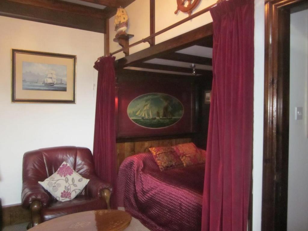 1 dormitorio con cama con dosel y cortinas rojas en White Owl Holiday Apartments, en Robin Hood's Bay