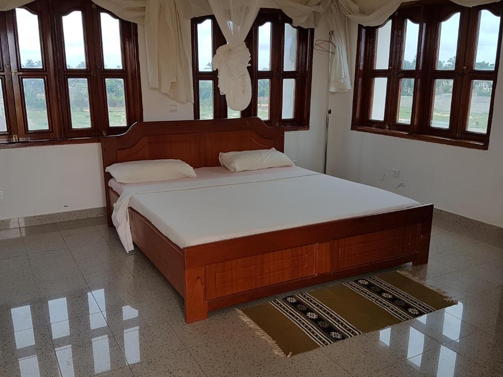 Cama grande en habitación con ventanas en Ramaya Auberge Espagnole, en Grand-Popo