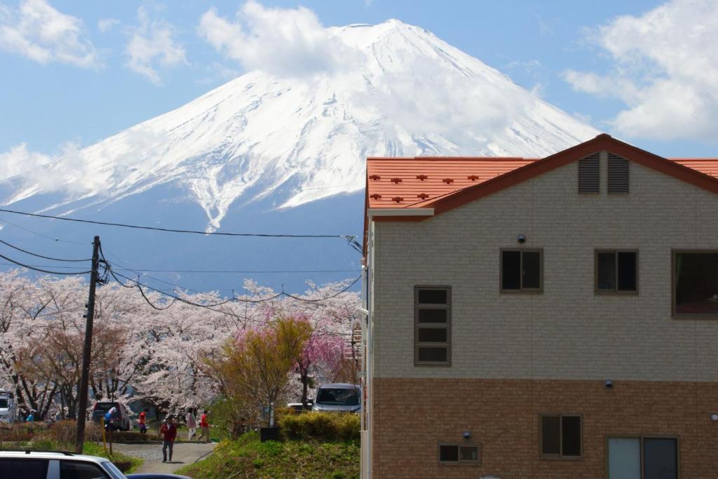 a snow covered mountain behind a house and a building at Cottage Pastorale in Fujikawaguchiko